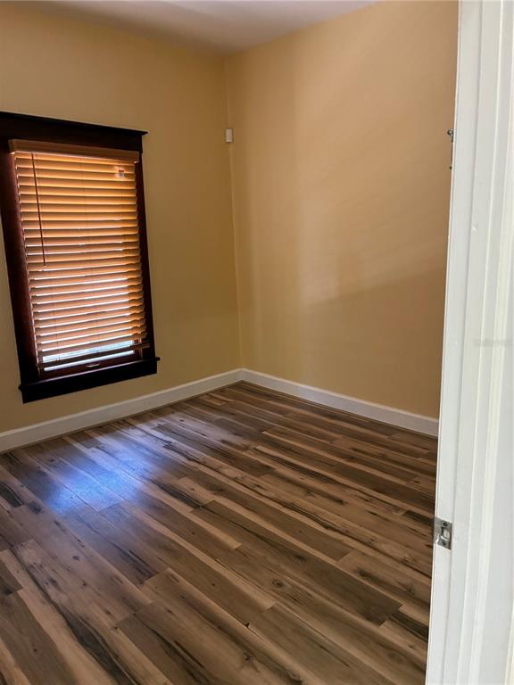 An empty room with light-colored walls, wood-look flooring, and a window with dark wood blinds — 814 N MAIN STREET, KISSIMMEE, FL