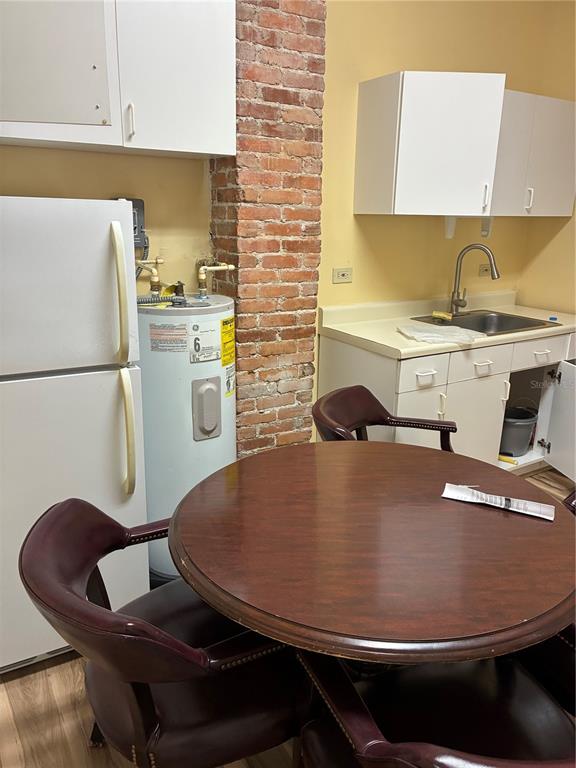 A kitchen features a round table, white cabinets, a sink, and an exposed brick column — 814 N MAIN STREET, KISSIMMEE, FL