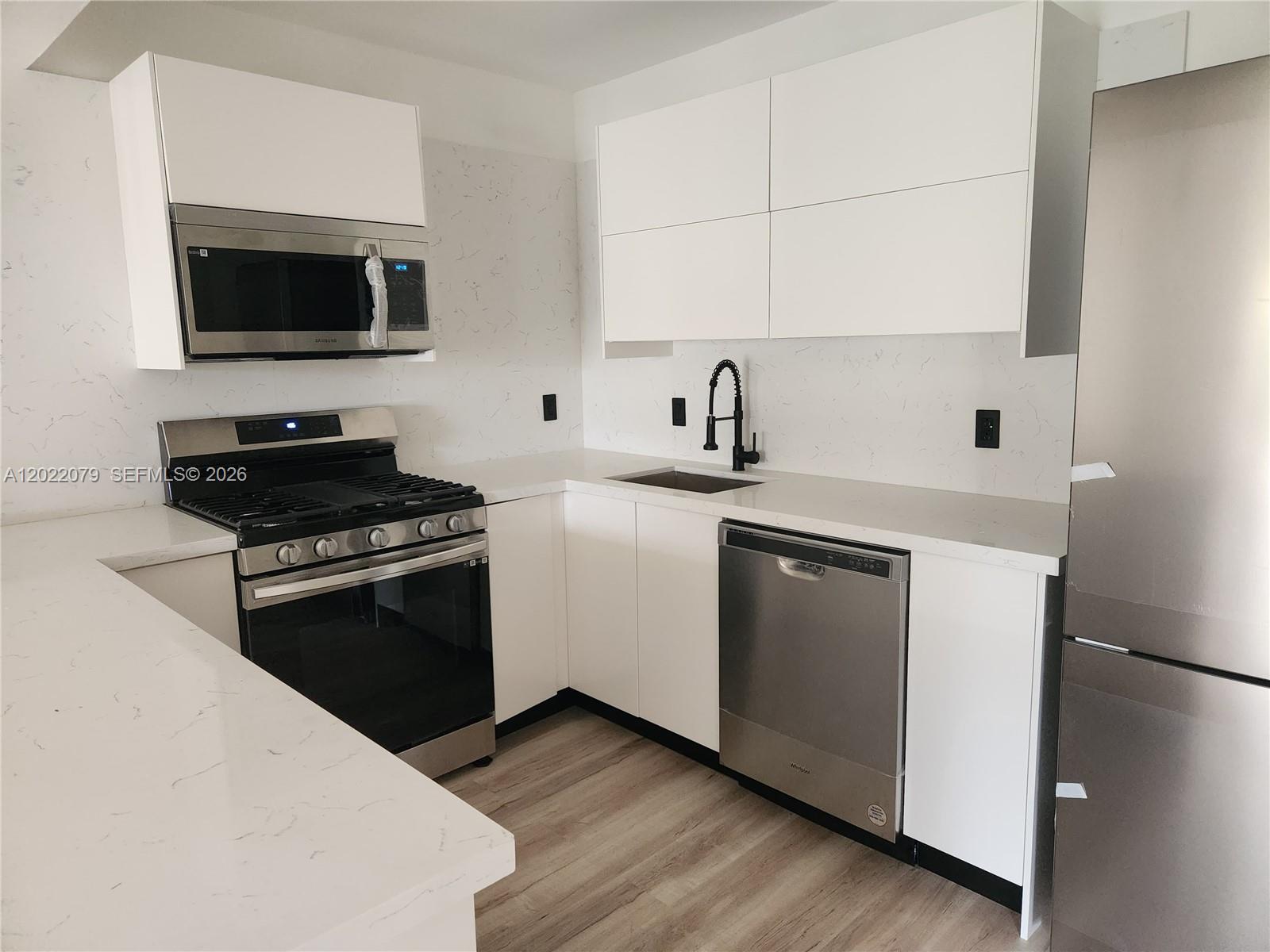 A modern kitchen features white cabinets, stainless steel appliances, and white marble-patterned countertops — 15315 SW 106th Ter # 433, Miami FL 33196, MIAMI, FL