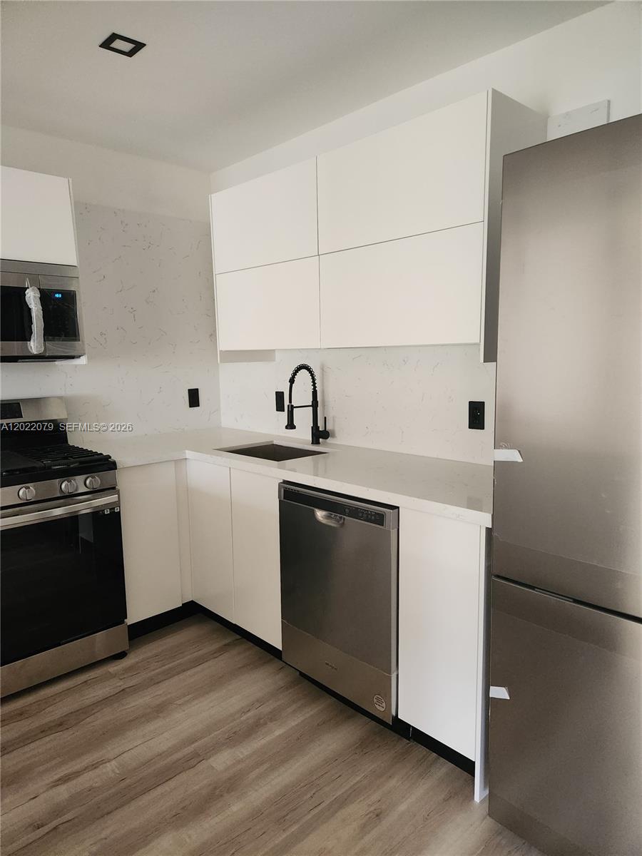A modern kitchen features white cabinets, stainless steel appliances, and a marble-patterned backsplash — 15315 SW 106th Ter # 433, Miami FL 33196, MIAMI, FL
