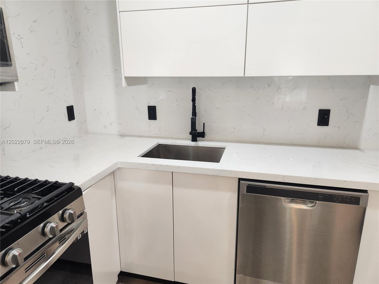 A modern kitchen features white cabinets, marble-patterned countertops, a stainless steel sink, and appliances — 15315 SW 106th Ter # 433, Miami FL 33196, MIAMI, FL
