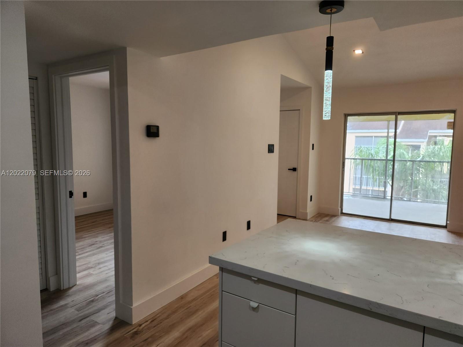 A kitchen island with a marble countertop sits in front of a doorway and balcony — 15315 SW 106th Ter # 433, Miami FL 33196, MIAMI, FL