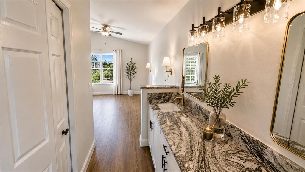 A bathroom vanity with granite countertops and gold fixtures overlooks an adjacent bedroom area — 1712 ERIN BROOKE DRIVE, VALRICO, FL