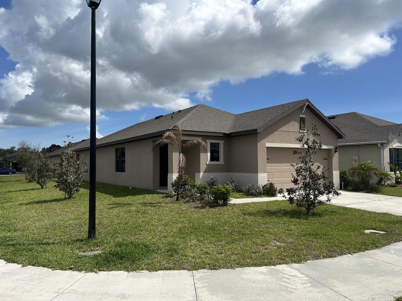 A tan single-story house with a two-car garage and a small front yard — 5414 Delight Drive, Fort Pierce FL 34947, FORT PIERCE, FL
