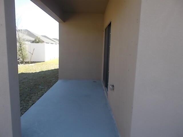 A covered concrete patio extends from a beige stucco wall toward a fenced backyard — 5414 Delight Drive, Fort Pierce FL 34947, FORT PIERCE, FL