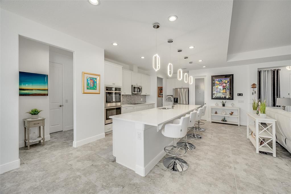 A modern white kitchen features a large island with bar seating and tile flooring — 375 LOYMER CIRCLE, MERRITT ISLAND, FL