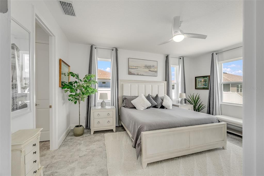 A bedroom features a white bed frame, gray bedding, tile floors, and two windows — 375 LOYMER CIRCLE, MERRITT ISLAND, FL