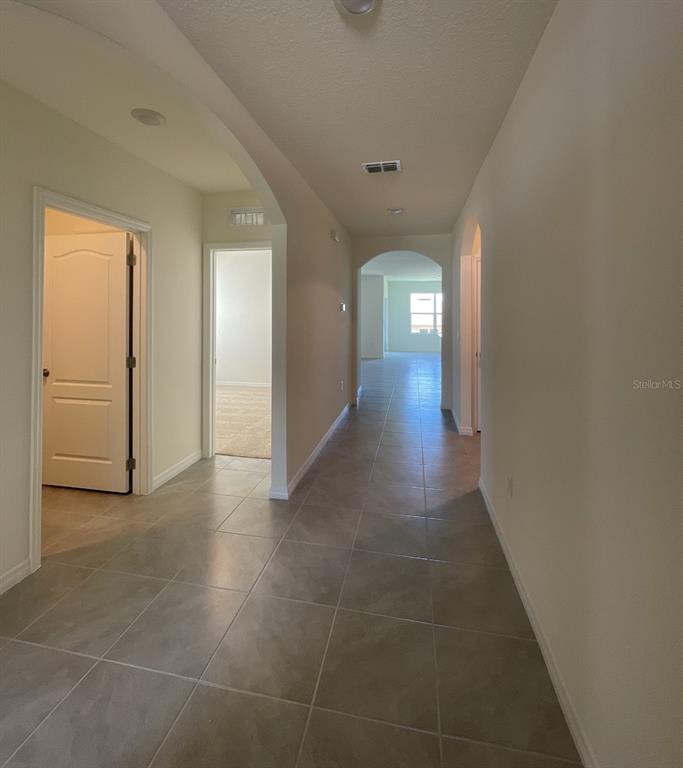 A tiled hallway leads past two doorways toward an open living area with large windows — 1779 BUCKEYE ROAD, DAVENPORT, FL