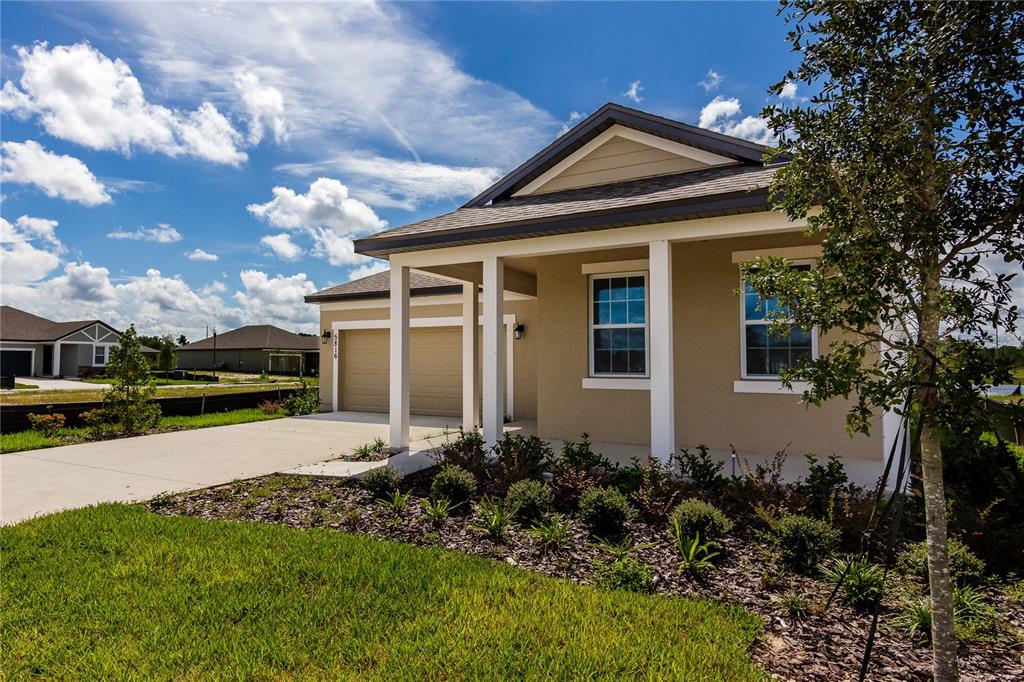 A tan single-story house with a two-car garage and a covered front porch — 5816 BAR RANCH ROAD, ST CLOUD, FL