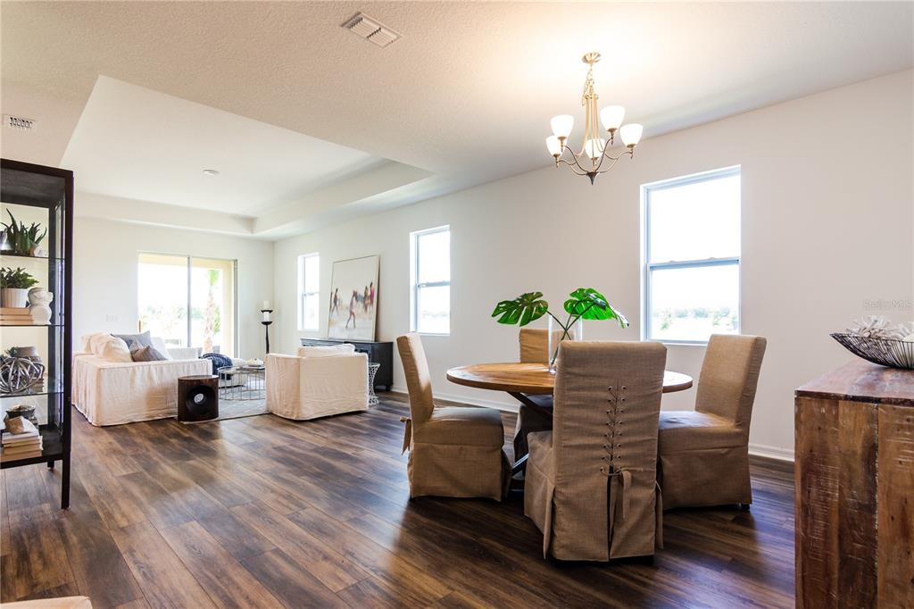 An open-concept living and dining area features wood-look flooring, neutral furniture, and a chandelier — 5816 BAR RANCH ROAD, ST CLOUD, FL