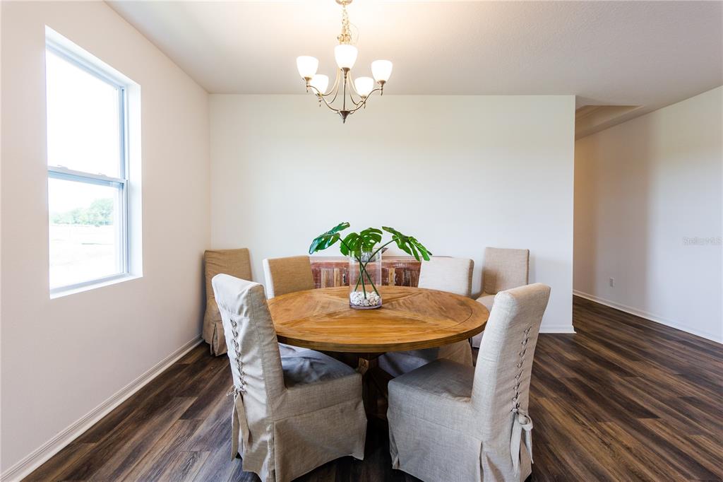 A dining room features a round wooden table, six slipcovered chairs, and a chandelier — 5816 BAR RANCH ROAD, ST CLOUD, FL
