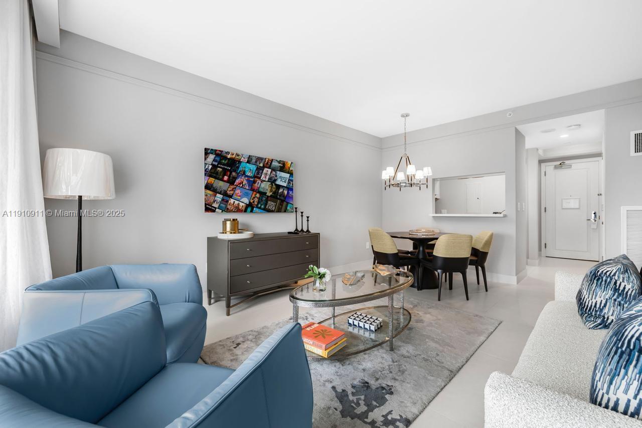 A living and dining area features blue armchairs, a glass coffee table, and a television — 1435 Brickell Ave # 3410, Miami FL 33131, MIAMI, FL
