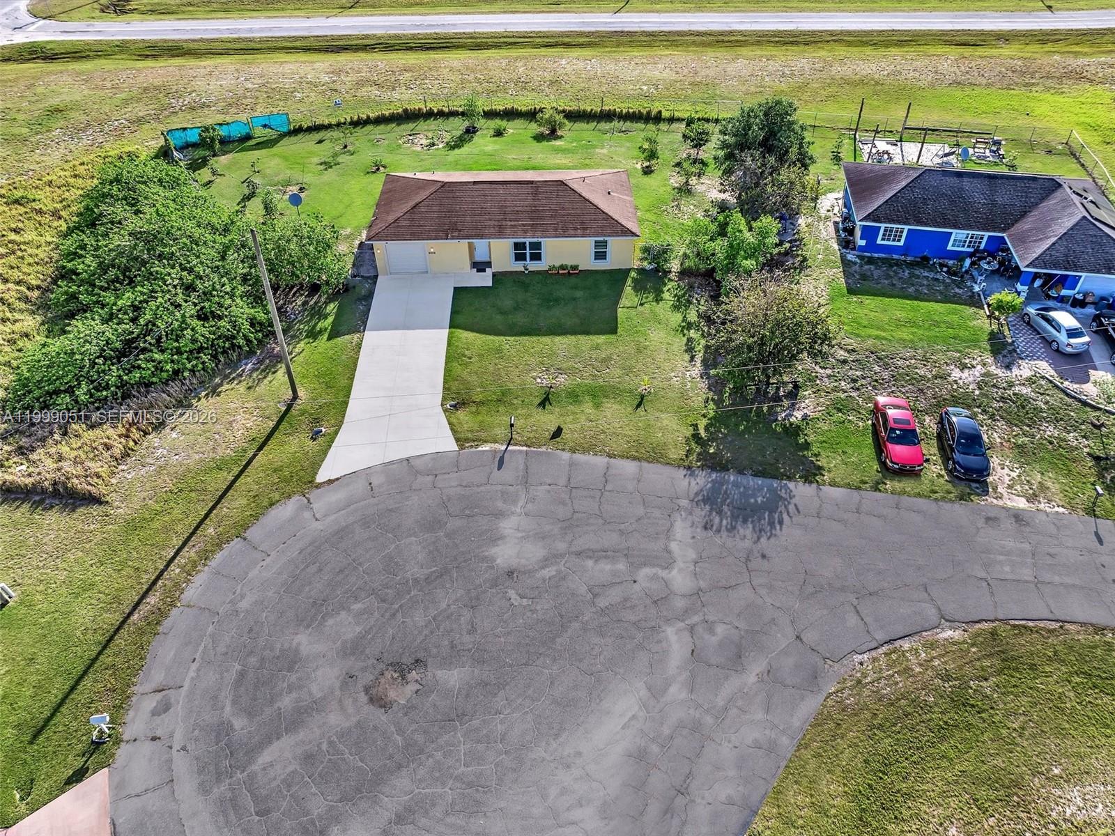 An aerial view shows a yellow house with a brown roof, driveway, and large yard — 9006 ABEL, La Belle FL 33935, LA BELLE, FL