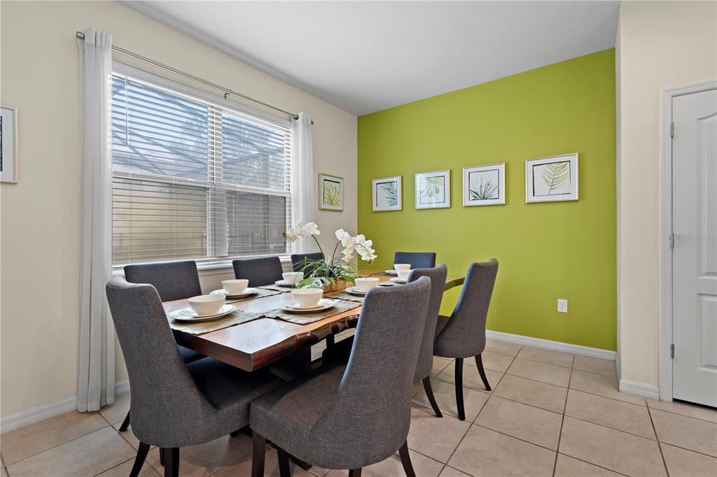 A dining room features a wooden table, six gray chairs, and a lime green accent wall — 1512 MUMBAI WAY, KISSIMMEE, FL