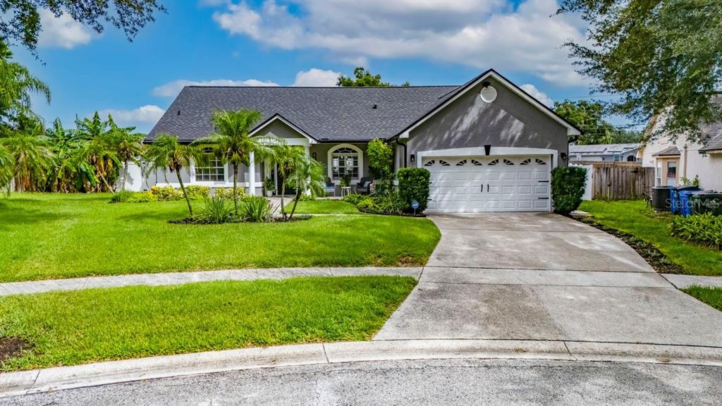A single-story gray house with a two-car garage and a landscaped front yard — 829 GREENBELT CIRCLE, BRANDON, FL