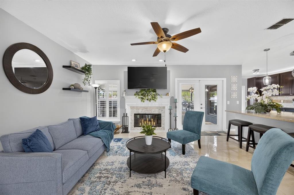 A living room features a fireplace, a blue sofa, two chairs, and a ceiling fan — 829 GREENBELT CIRCLE, BRANDON, FL