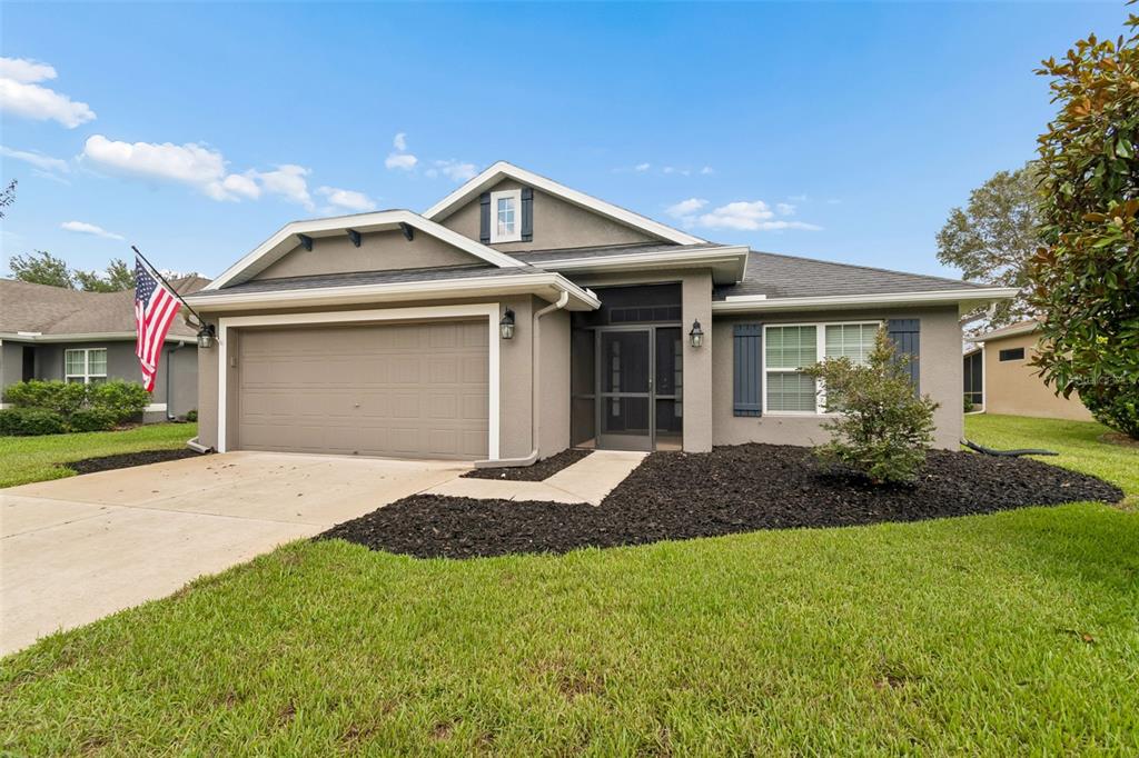 A single-story house with a beige stucco exterior, a two-car garage, and a screened entryway — 13428 MEADOW GOLF AVENUE, HUDSON, FL
