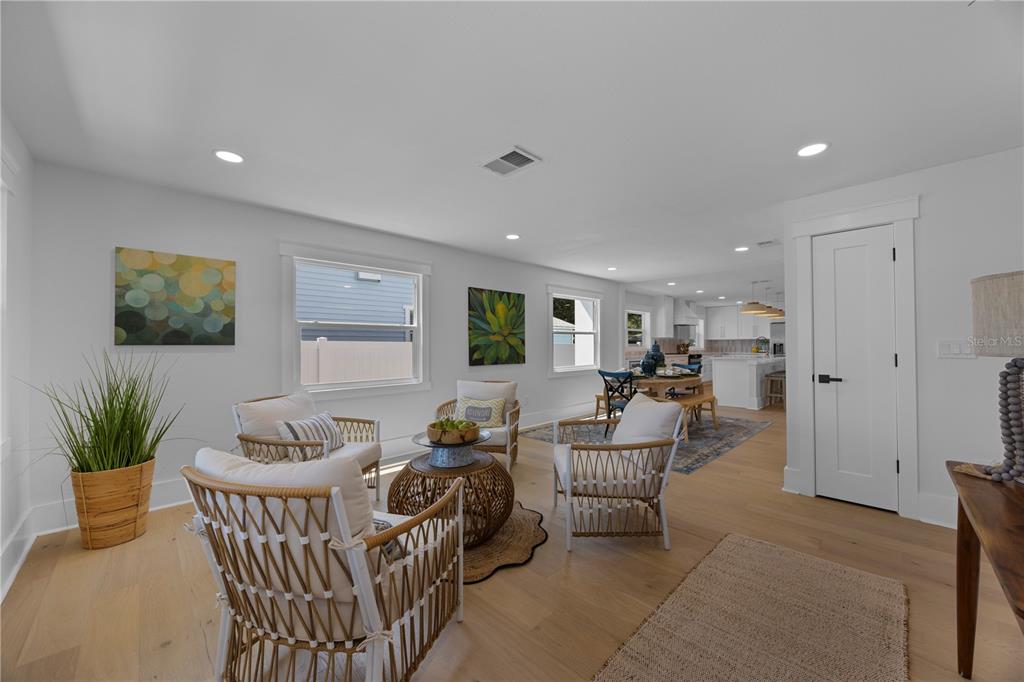 A bright living room features light wood floors, white walls, and woven accent chairs — 4621 4TH AVENUE N, ST PETERSBURG, FL