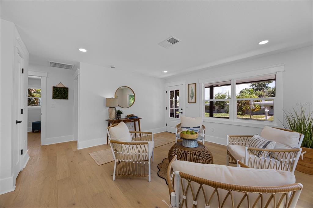 A bright living room features light wood floors, white walls, and three woven armchairs — 4621 4TH AVENUE N, ST PETERSBURG, FL