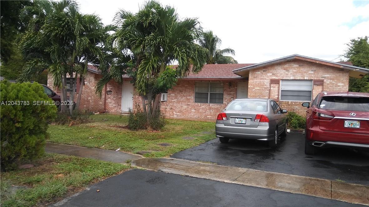 A single-story brick house with a paved driveway, two parked cars, and palm trees — 5425 NW 16th Ct # 0, Lauderhill FL 33313, LAUDERHILL, FL
