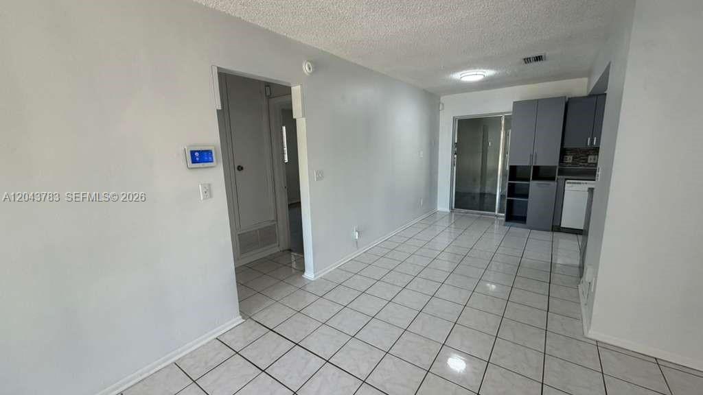A room with white tiled floors, light gray walls, and a small kitchen area — 5425 NW 16th Ct # 0, Lauderhill FL 33313, LAUDERHILL, FL