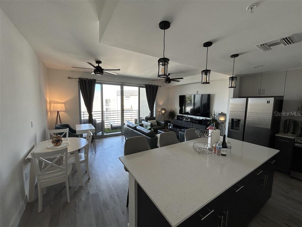 An open-concept kitchen and living area features a large island, dining table, and balcony access — 1703 N TAMIAMI TRAIL UNIT 510, SARASOTA, FL