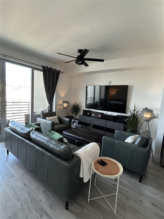 A living room features a dark leather sofa, matching armchairs, a television, and wood flooring — 1703 N TAMIAMI TRAIL UNIT 510, SARASOTA, FL