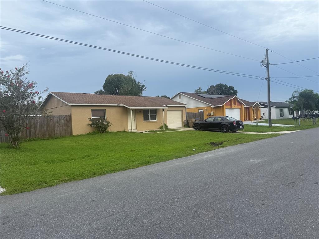 A tan single-story house with a garage and a large front lawn — 235 BALBOA DRIVE, KISSIMMEE, FL