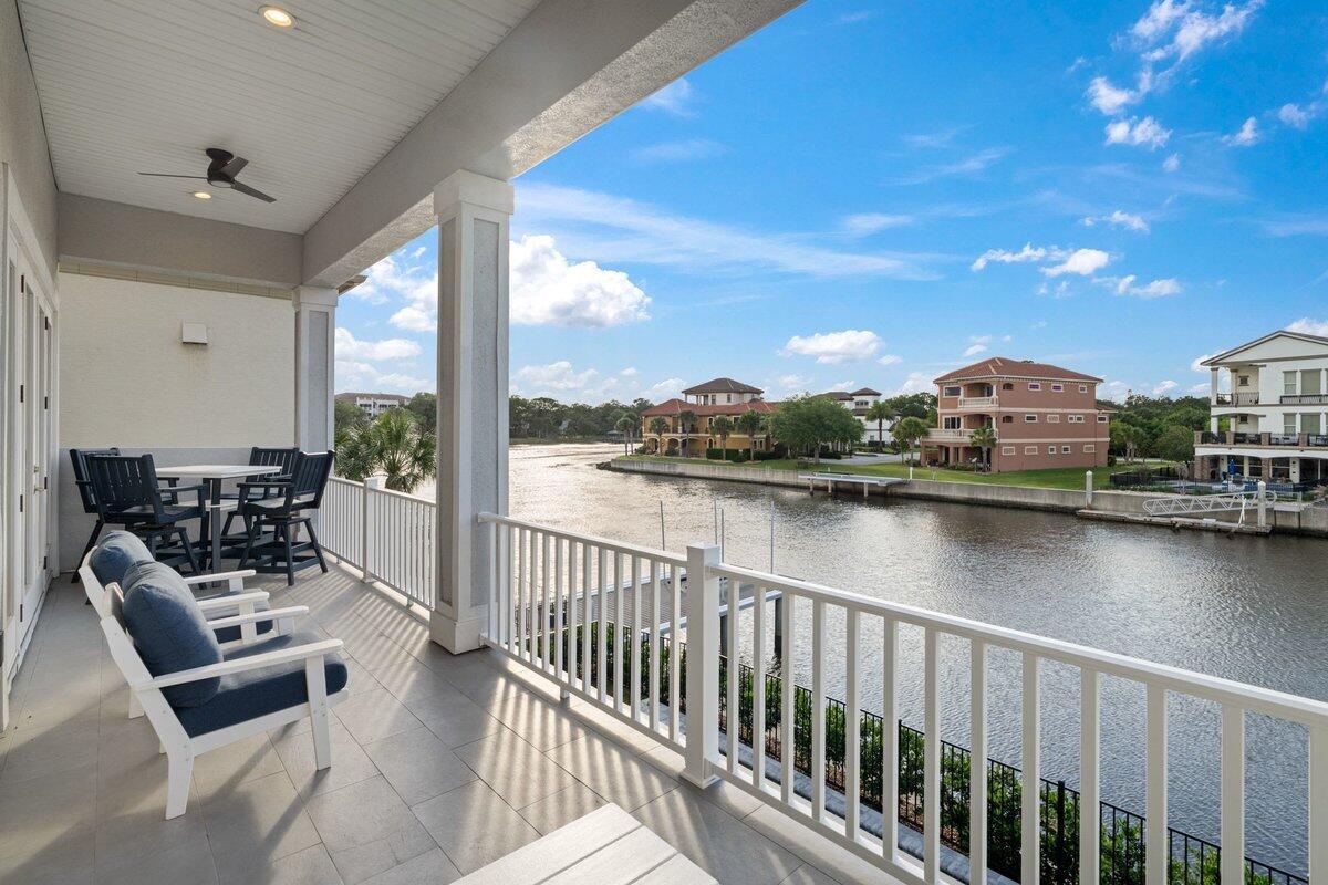 A covered balcony with outdoor furniture overlooks a canal lined with multi-story houses — 18 Spinaker Circle, Palm Coast FL 32137, PALM COAST, FL