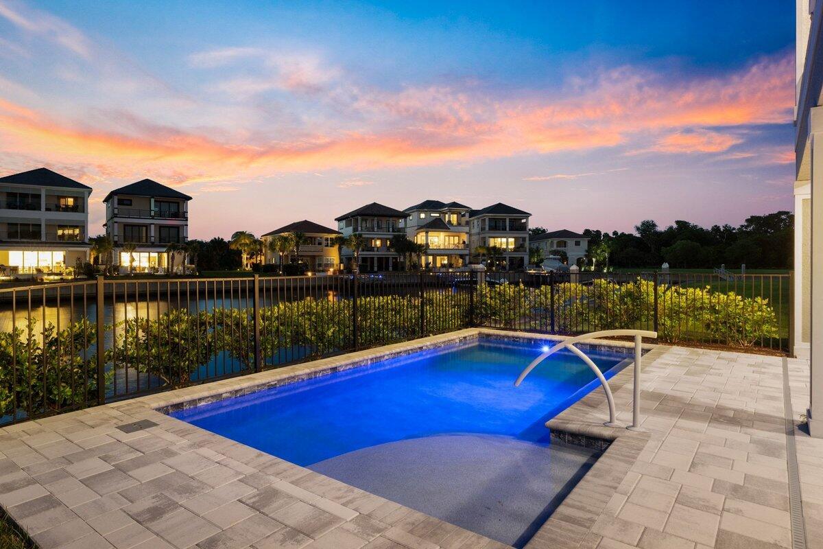 A small rectangular swimming pool sits on a paved patio overlooking a canal and houses — 18 Spinaker Circle, Palm Coast FL 32137, PALM COAST, FL