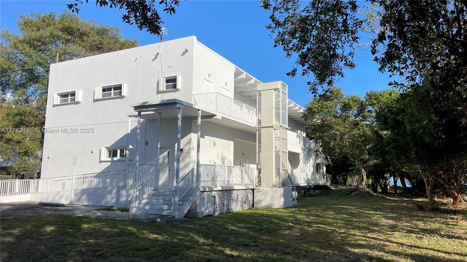 A white two-story building features an exterior elevator shaft and a staircase leading to balconies — 14 125th Street Gulf, Marathon FL 33050, MARATHON, FL