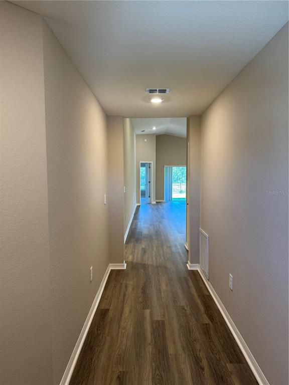 A hallway with wood-look flooring leads to an open living area with a sliding door — 3902 WRENWOOD DRIVE, LAKELAND, FL