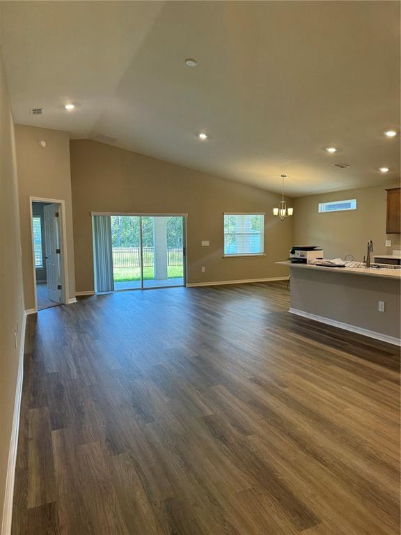 An open-concept living area features wood-look flooring, a vaulted ceiling, and a kitchen island — 3902 WRENWOOD DRIVE, LAKELAND, FL