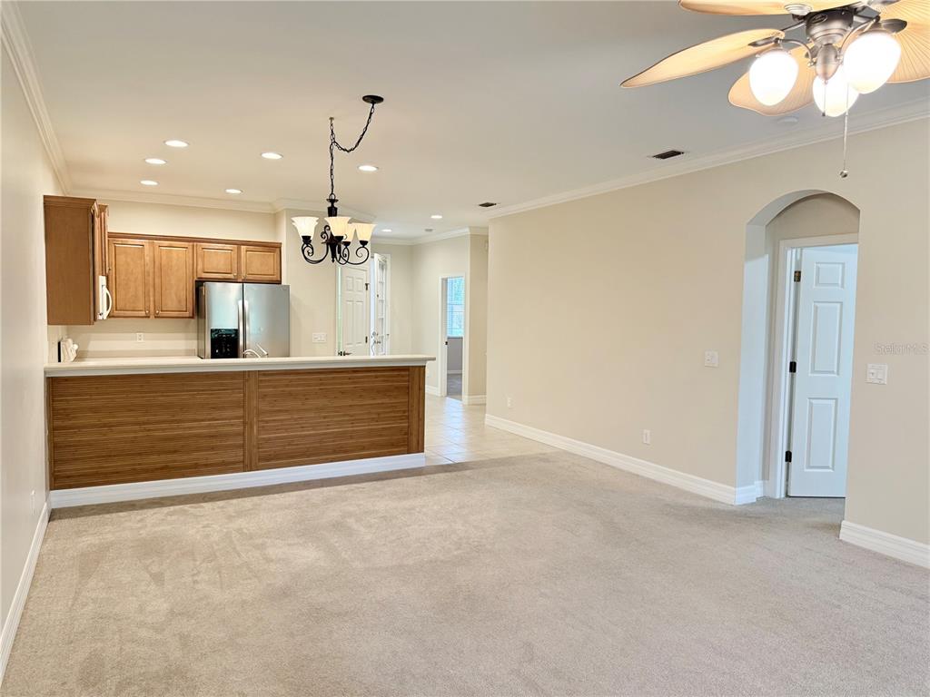 A carpeted living room opens to a kitchen with a wood-paneled breakfast bar — 11479 52ND COURT E, PARRISH, FL