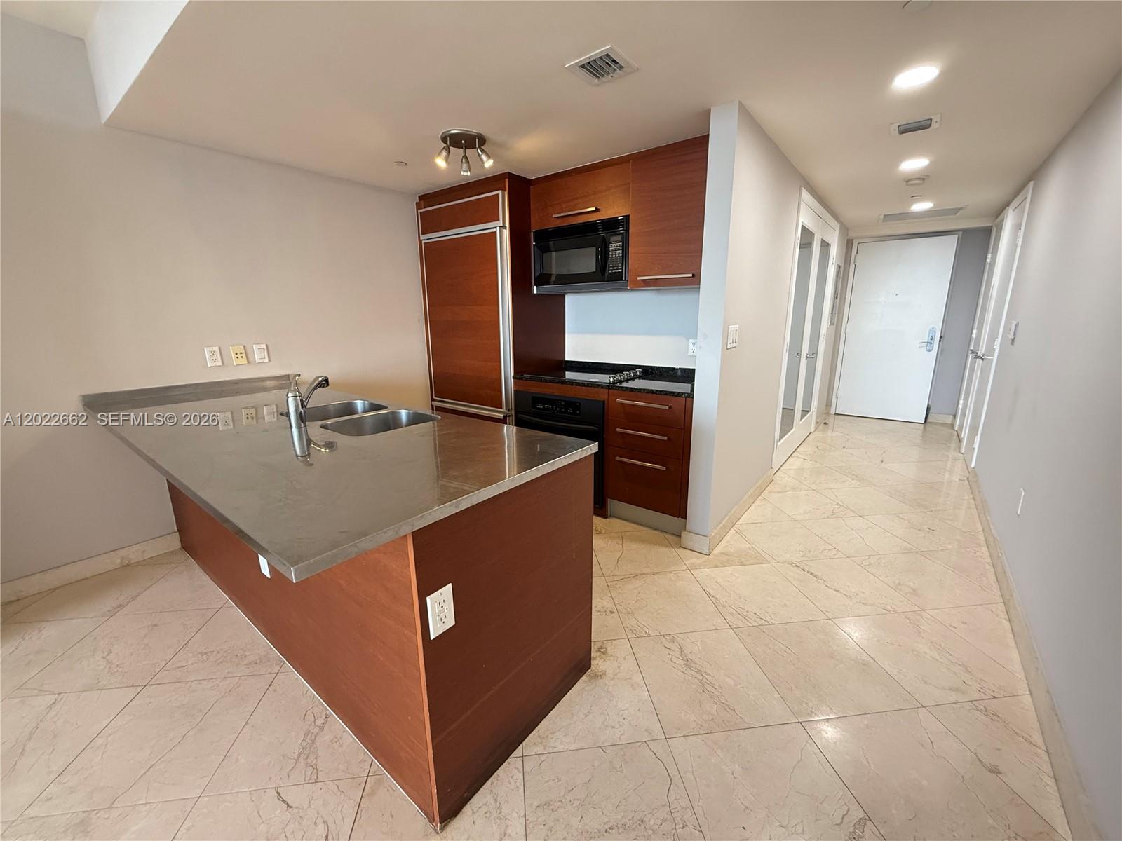 A kitchen features a stainless steel island countertop, wood cabinetry, and light-colored tile flooring — 1850 S OCEAN DR # 4009, Hallandale Beach FL 33009, HALLANDALE BEACH, FL