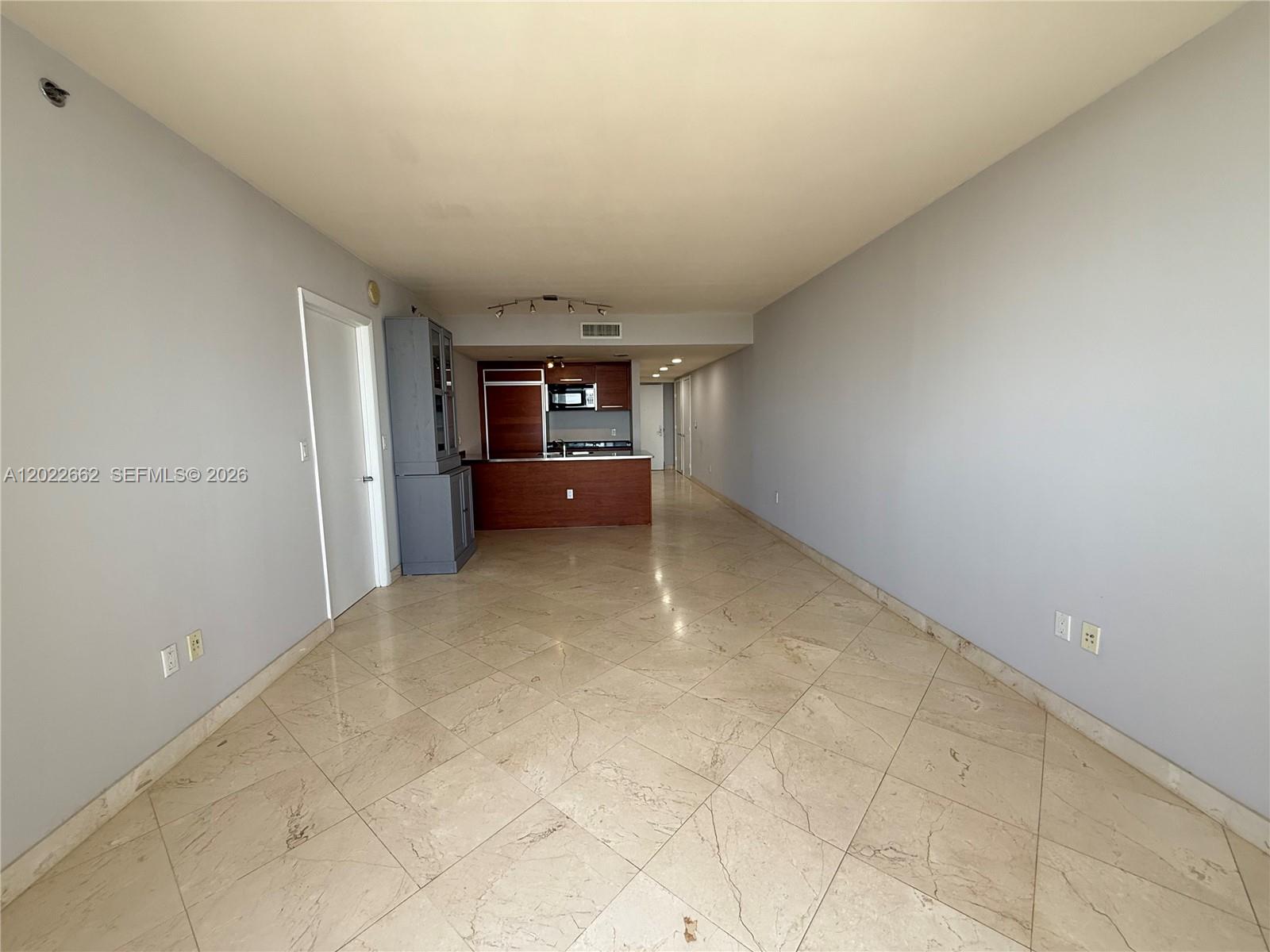 An open-concept living area features light-colored tile flooring, gray walls, and a kitchen with wood cabinetry — 1850 S OCEAN DR # 4009, Hallandale Beach FL 33009, HALLANDALE BEACH, FL