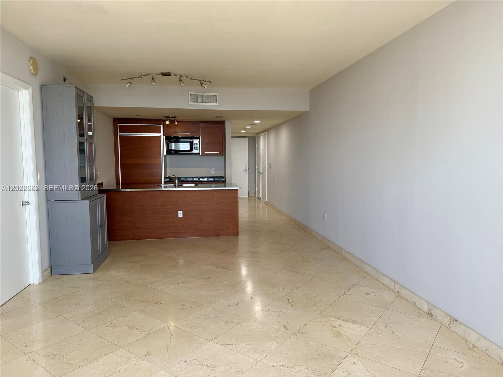 A kitchen with wood cabinetry and a large open living area with tiled floors — 1850 S OCEAN DR # 4009, Hallandale Beach FL 33009, HALLANDALE BEACH, FL