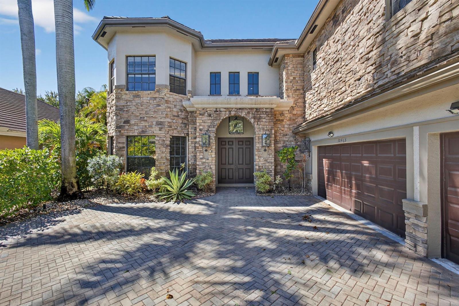 A two-story house with stone veneer, a brick paver driveway, and a double garage — 10468 Trianon Place, Wellington FL 33449, WELLINGTON, FL
