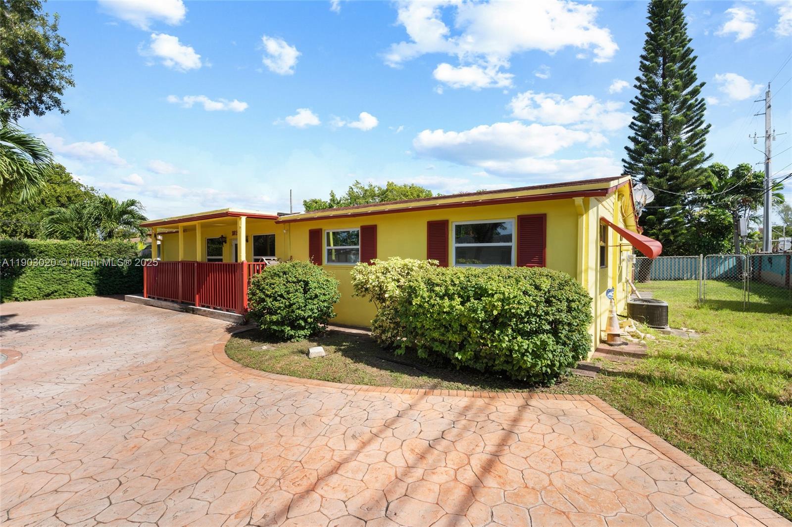 A yellow single-story house features red shutters, a covered porch, and a stamped concrete driveway — 18151 NE 9th Ct, North Miami Beach FL 33162, NORTH MIAMI BEACH, FL