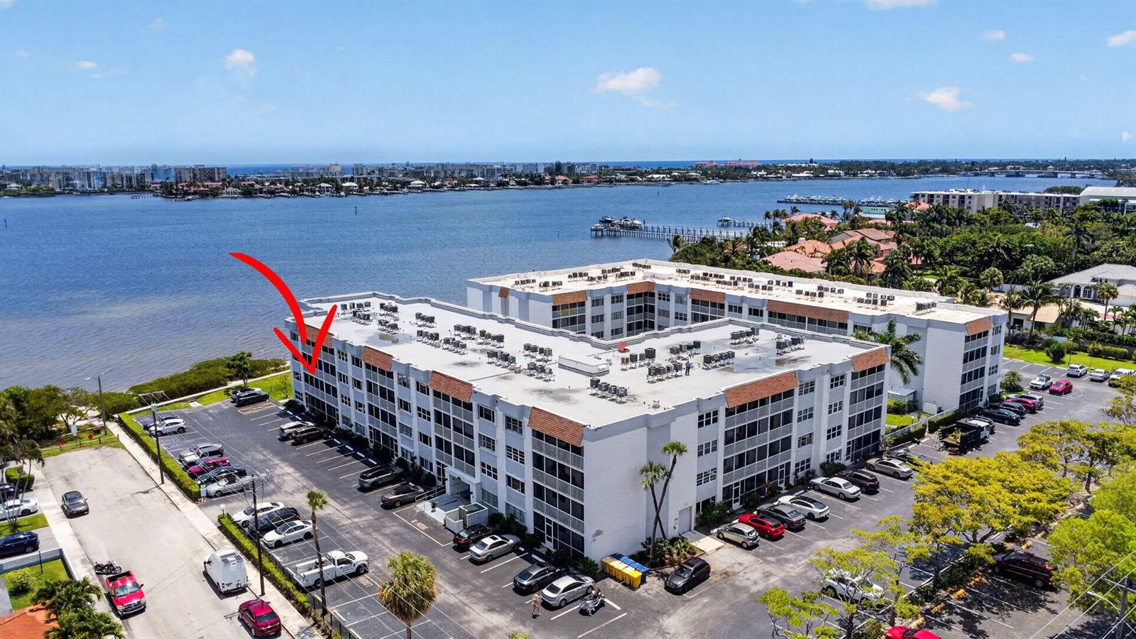 An aerial view shows a multi-story apartment building situated along a waterfront with parking lots — 1502 S Lakeside Drive # 214, FL 33460, FL