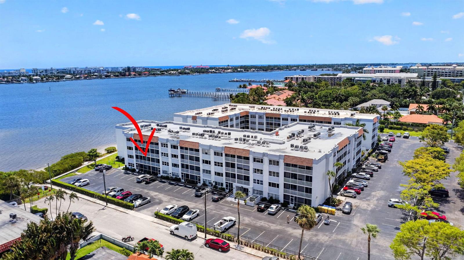 An aerial view shows a multi-story waterfront apartment building with a parking lot — 1502 S Lakeside Drive # 214, FL 33460, FL