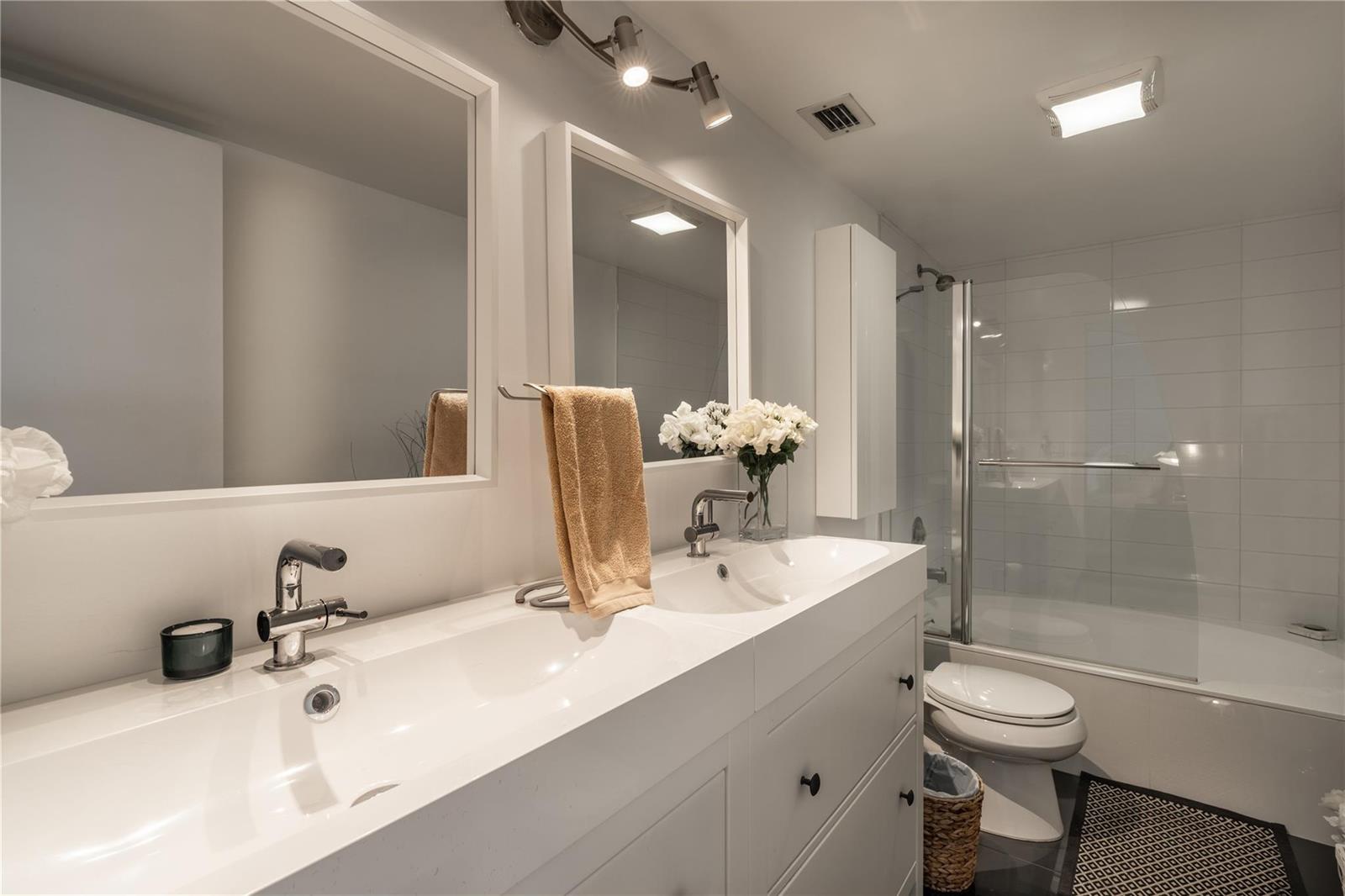 A modern bathroom features a double vanity with white countertops, two mirrors, and a tub-shower — 2206 S Cypress Bend Drive # 803, Pompano Beach FL 33069, POMPANO BEACH, FL