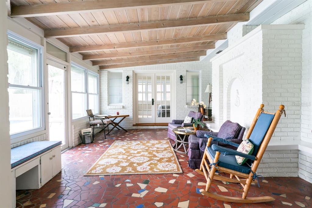 A sunroom with a wood-beamed ceiling, white brick walls, and a red mosaic tile floor — 1200 W LAKE OTIS DRIVE SE, WINTER HAVEN, FL