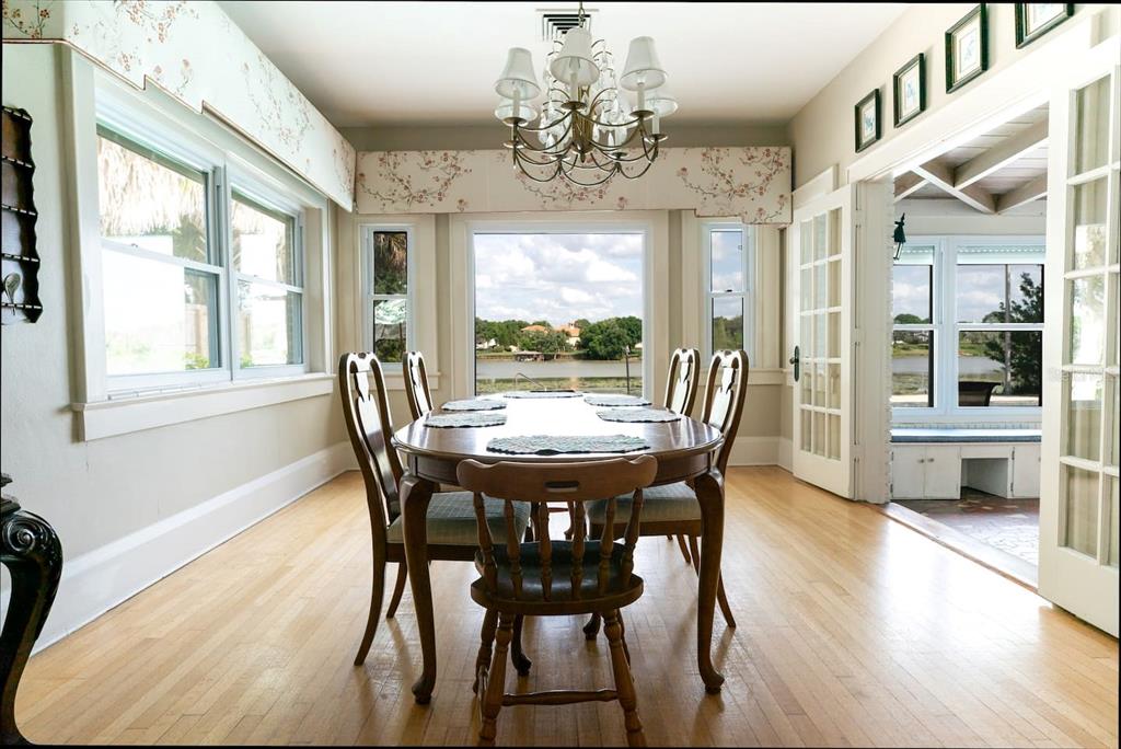 A dining room with a wooden table, chairs, chandelier, and large windows overlooking a lake — 1200 W LAKE OTIS DRIVE SE, WINTER HAVEN, FL