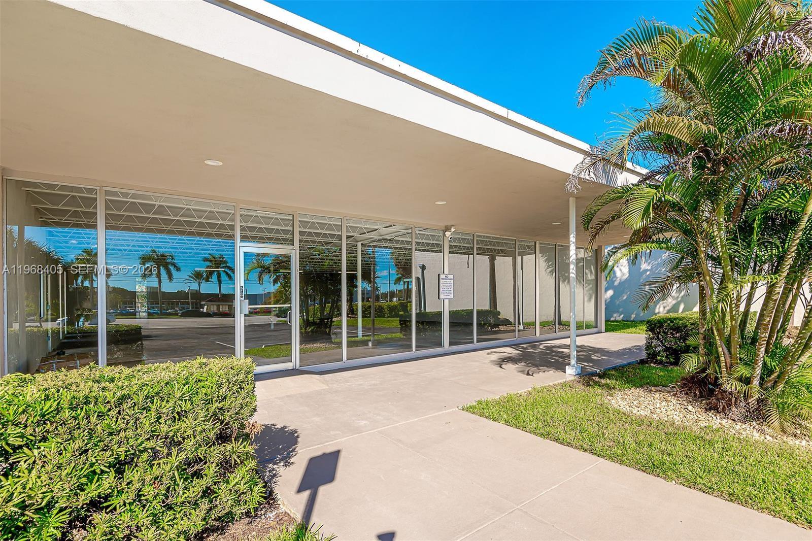 The exterior of a commercial building features a glass storefront, a concrete walkway, and landscaping — 2121 N State Road 7, Margate FL 33063, MARGATE, FL