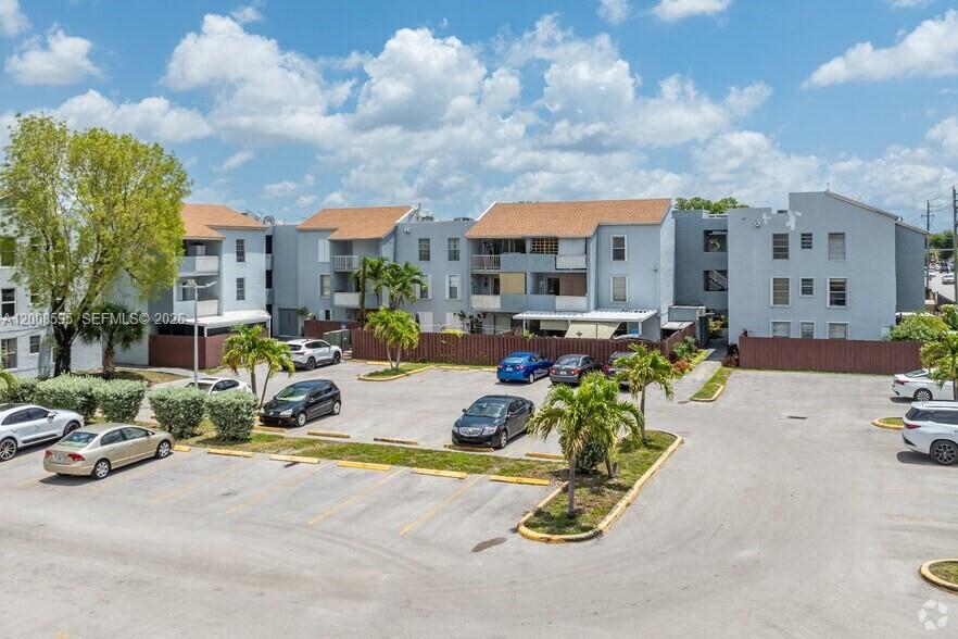 A multi-story blue apartment building features balconies, palm trees, and a parking lot — 6095 W 18th Ave # S219, Hialeah FL 33012, HIALEAH, FL
