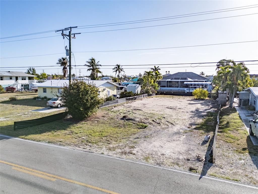 An elevated view shows a vacant, sandy residential lot situated between two existing houses — 3314 YORK ROAD, ST JAMES CITY, FL