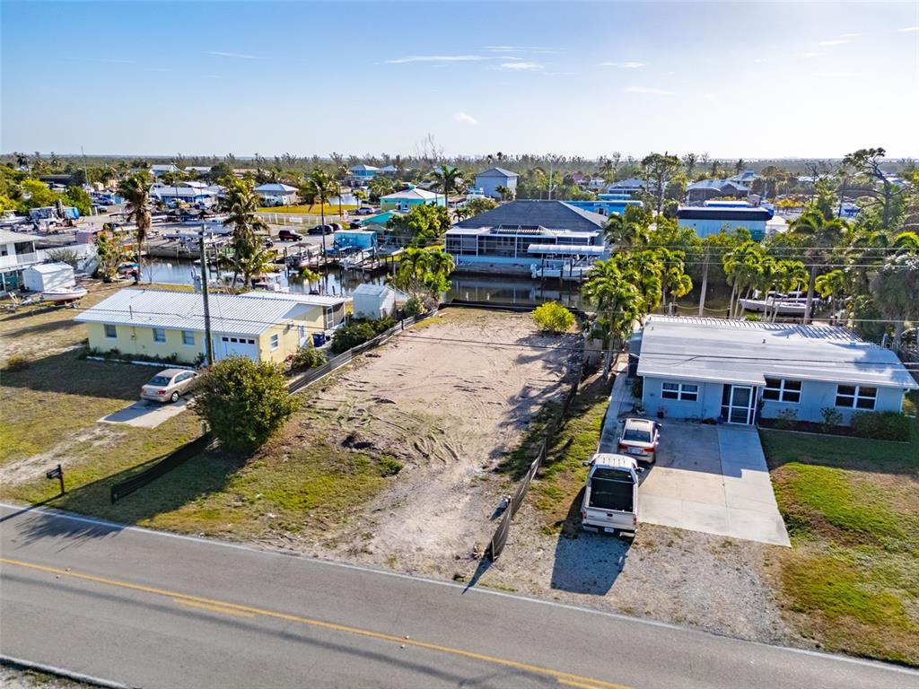 An aerial view shows a vacant lot situated between two houses near a canal — 3314 YORK ROAD, ST JAMES CITY, FL