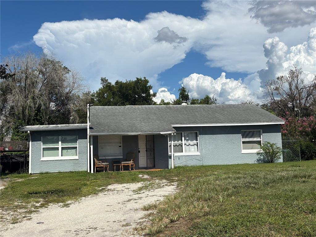 A single-story gray house with a gravel driveway and a small covered front porch — 687 WALKUP DRIVE, ORLANDO, FL