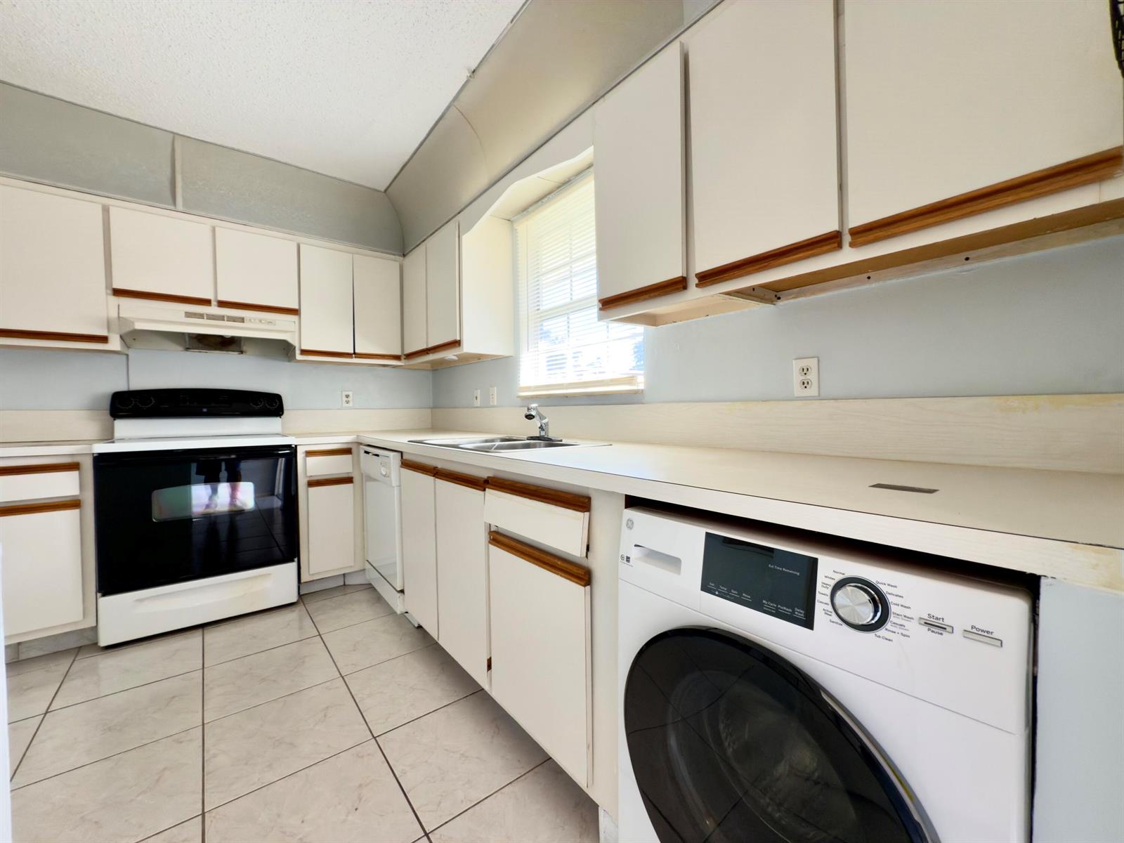 A kitchen features white cabinets with wood trim, a black oven, and a front-loading washer — 170 Amherst Lane, Lake Worth FL 33467, LAKE WORTH, FL